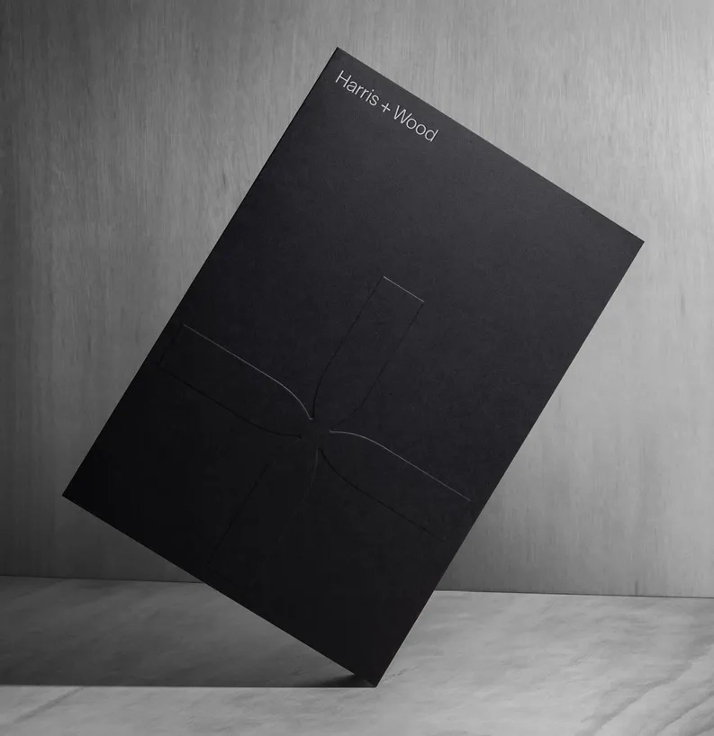 Black Harris + Wood presentation folder with embossed cross-shaped brand mark