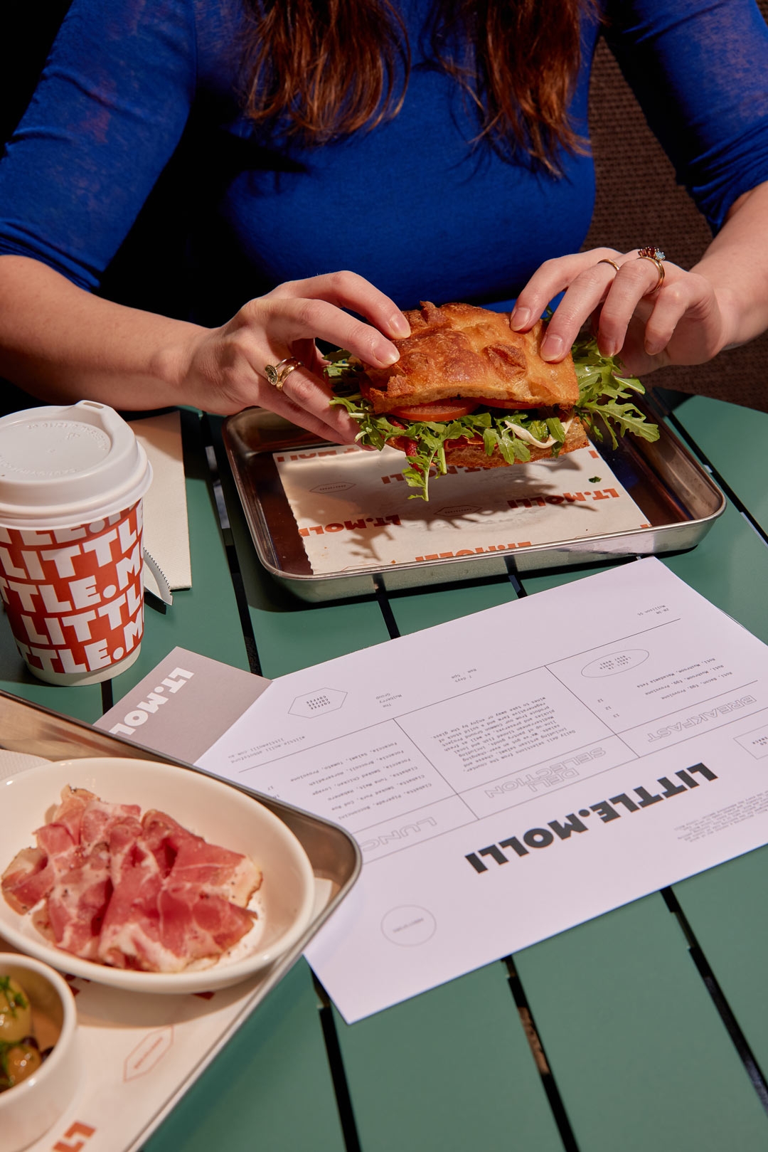 Little Molli table spread with focaccia sandwich, charcuterie plate, coffee cup and printed menu