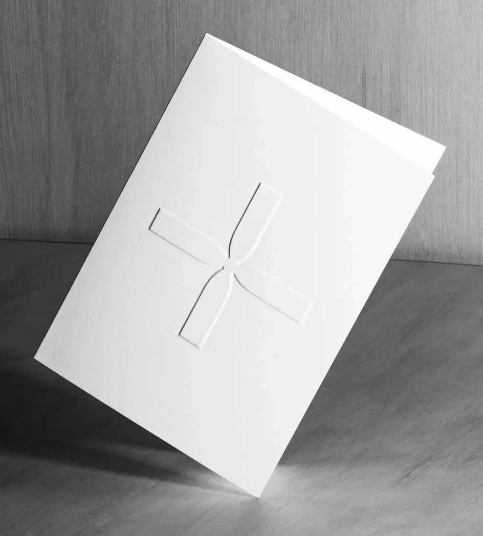 White embossed Harris + Wood thank you card standing on a light grey surface