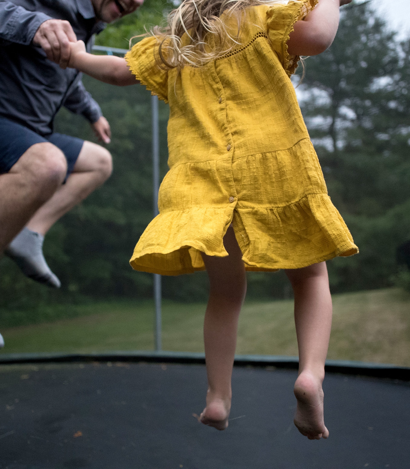 Father jumping on a trampoline with his child in the backyard